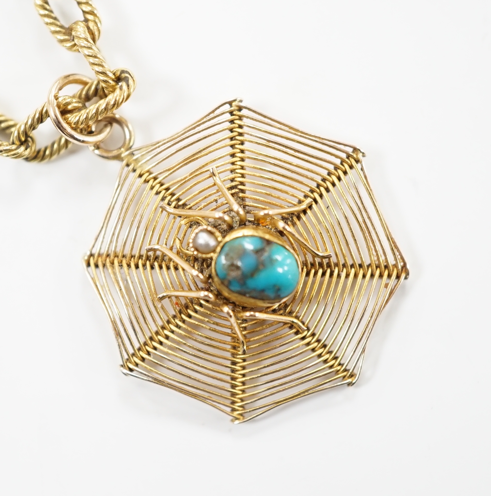 An early 20th century 9ct, turquoise and seed pearl set 'spider and web' pendant, 30mm, on a yellow metal chain, stamped 18 and numbered 2312, one link bearing the engraved word 'Cartier', 58cm, gross weight 23.2 grams.